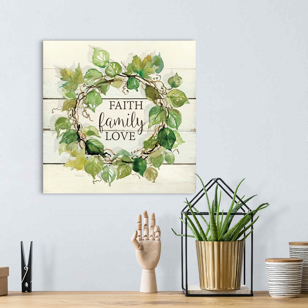 A bohemian room featuring A wreath of various watercolor leaves surround the words, "Faith, family, love" on shiplap.