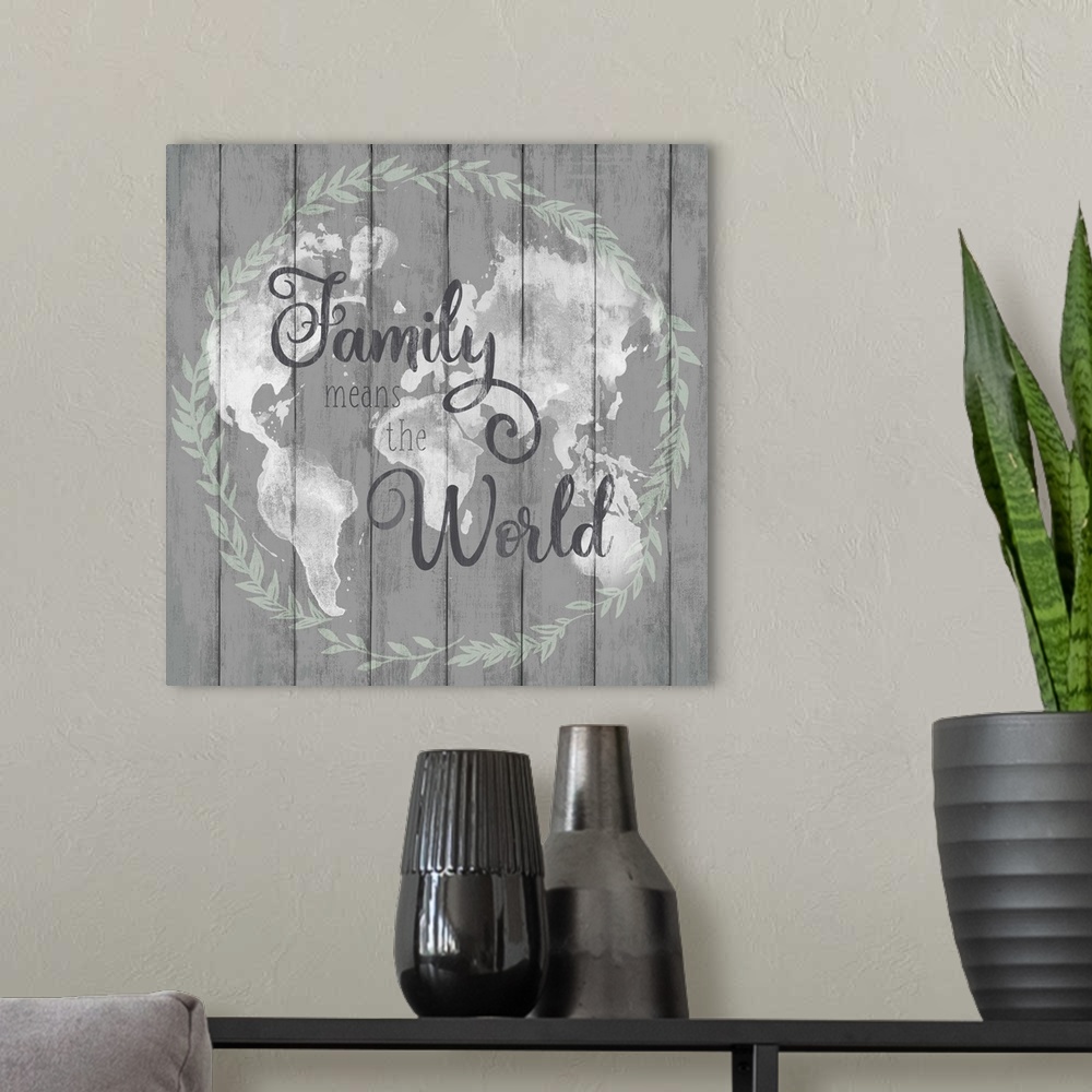 A modern room featuring Square decorative artwork of a map of world with a wreath around it and the text 'Family Means Th...