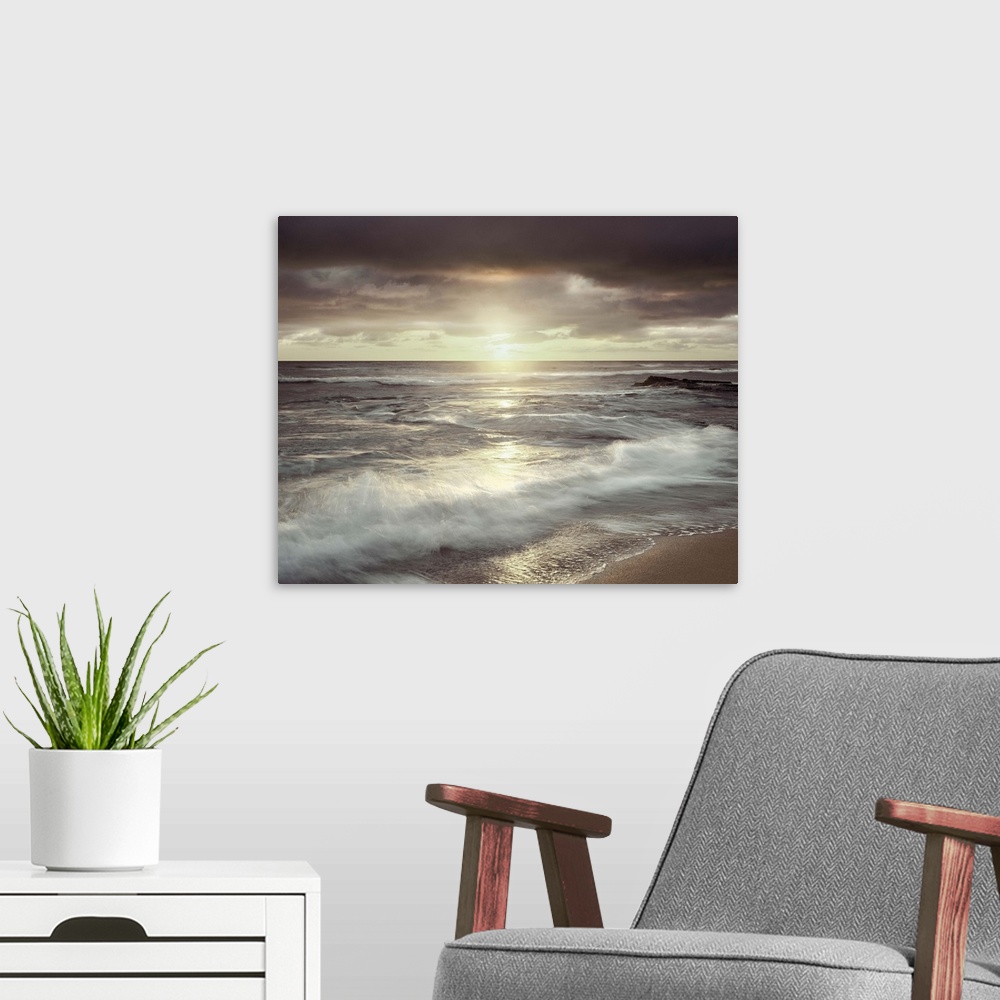 A modern room featuring Long exposure photograph of waves crashing on the shore with an evening sunset and a cloudy sky.
