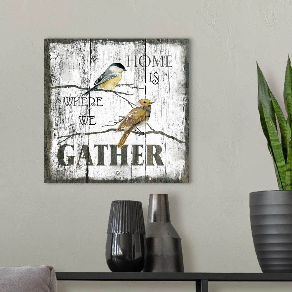 A modern room featuring A decorative painting of two birds sitting on branches and the text ?Home is Where We Gather? pai...