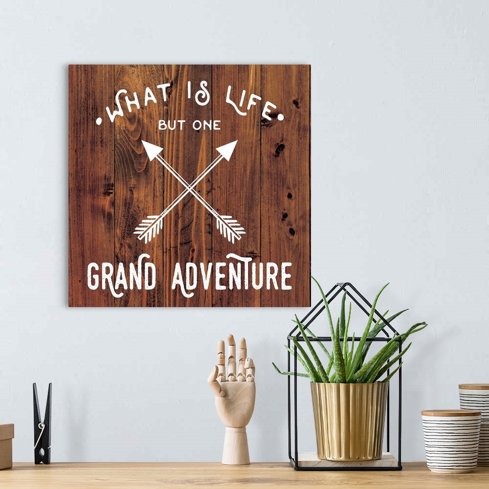 A bohemian room featuring Typography art reading "What is life but one grand adventure" with a crossed arrow design on a wo...