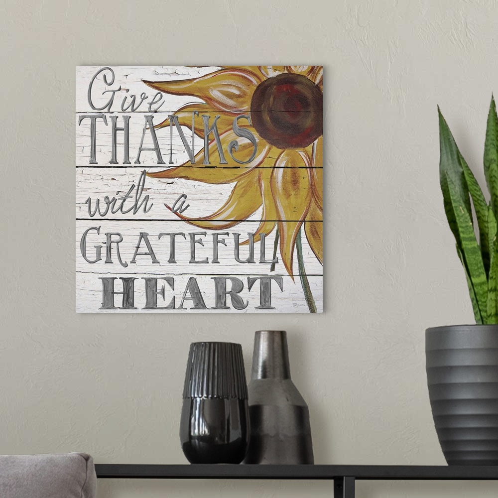 A modern room featuring "Give thanks with a grateful heart" handwritten on white shiplap background and sunflower.