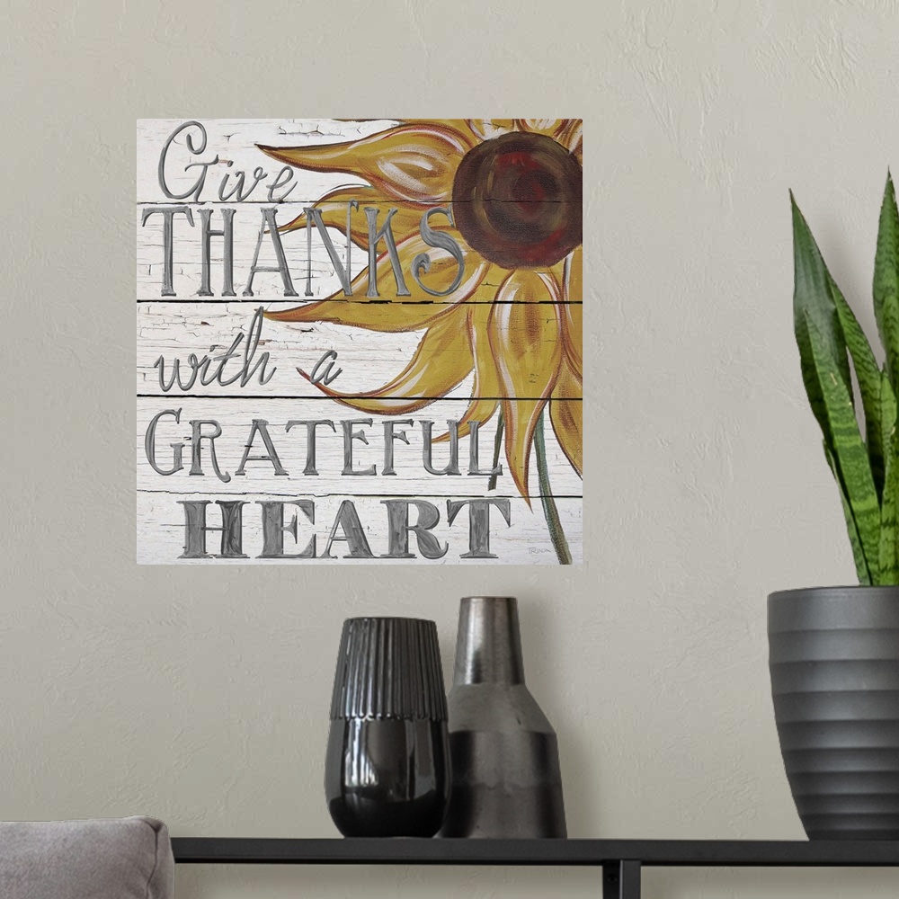 A modern room featuring "Give thanks with a grateful heart" handwritten on white shiplap background and sunflower.