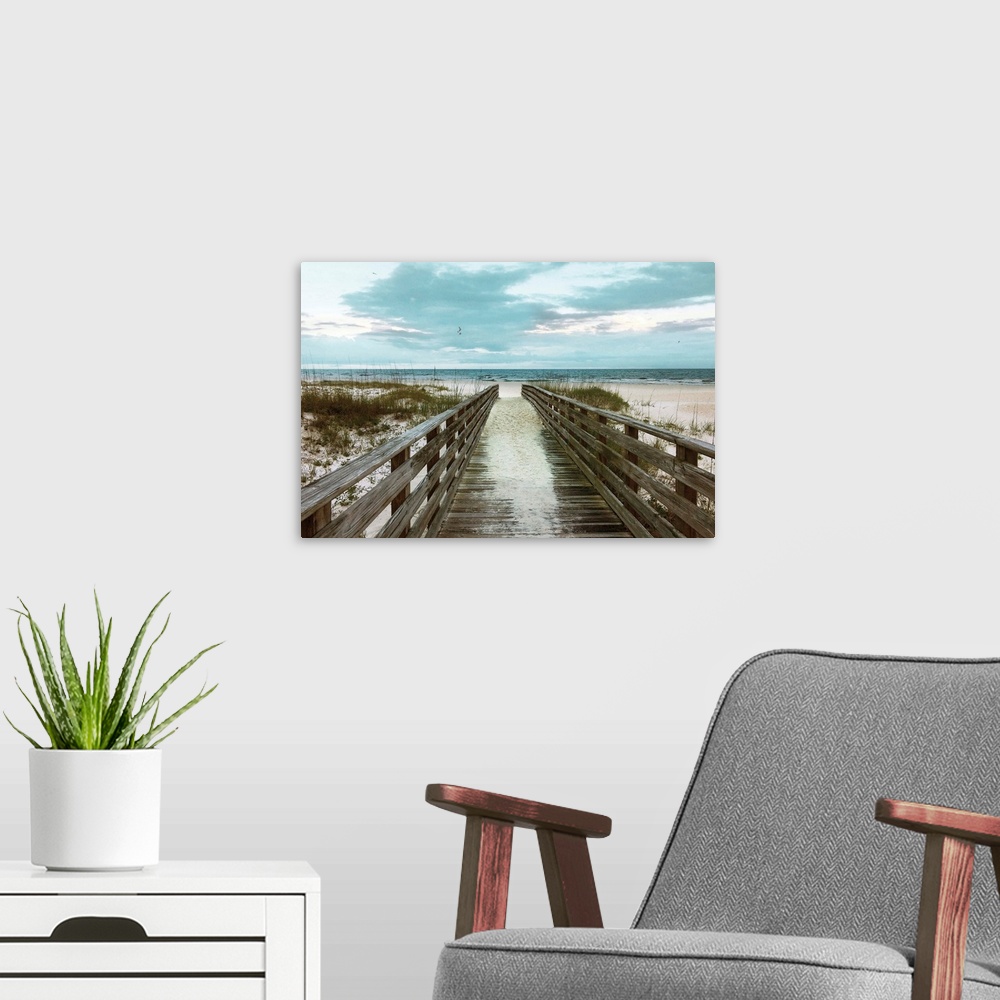 A modern room featuring A photo of a boardwalk leading to a sandy unoccupied beach.