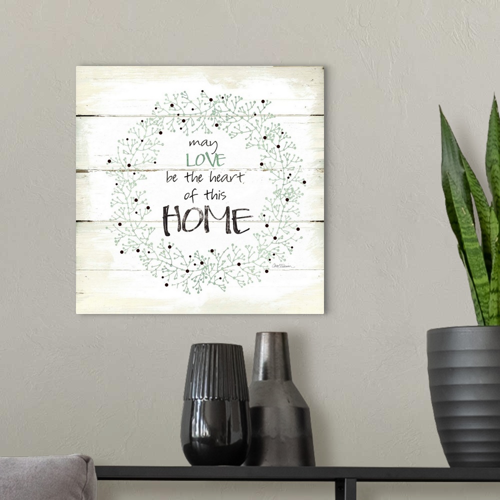 A modern room featuring A decorative painting of a wreath on an aged white wooden background with the phrase ?may LOVE be...