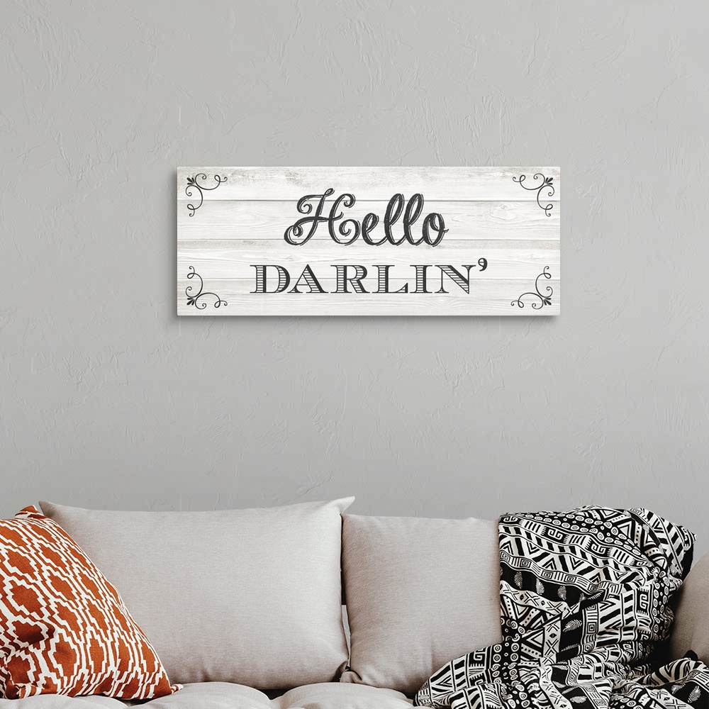A bohemian room featuring The southern sentiment "Hello darlin'" is black text placed on a faux wood texture adorned with e...