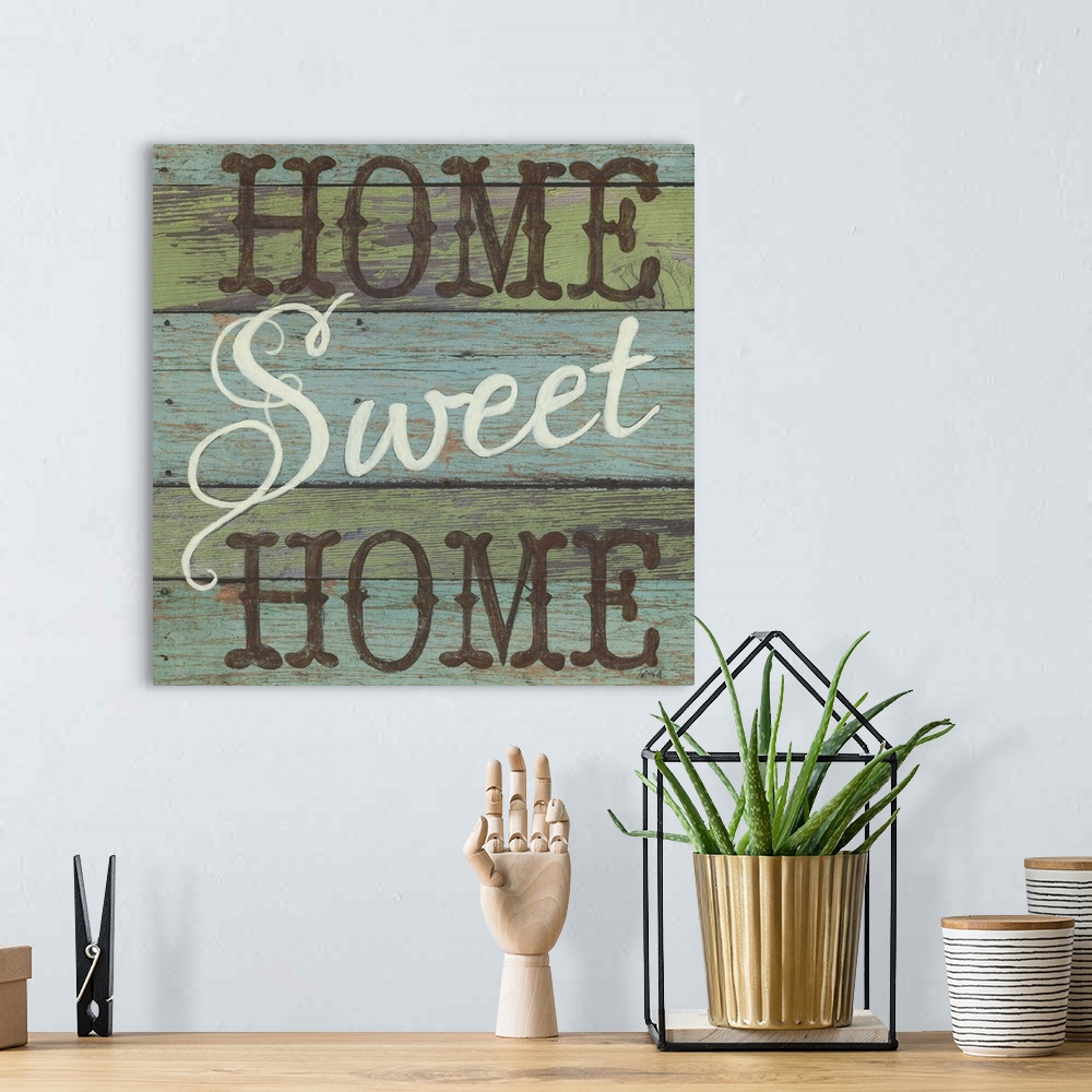 A bohemian room featuring A decorative square painting that says ?Home Sweet Home? on a blue and green striped wooden backg...