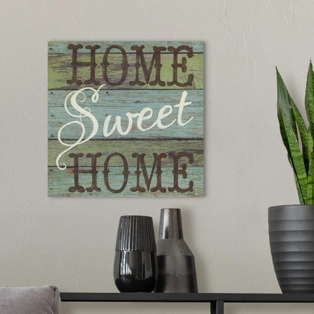 A modern room featuring A decorative square painting that says ?Home Sweet Home? on a blue and green striped wooden backg...