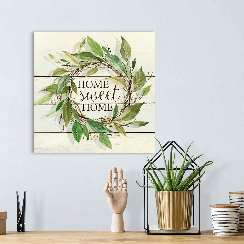 A bohemian room featuring A wreath of various watercolor leaves surround the words, "Home, sweet home" on shiplap.