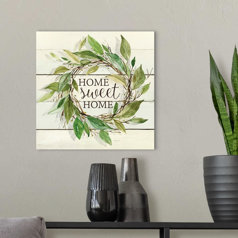 A modern room featuring A wreath of various watercolor leaves surround the words, "Home, sweet home" on shiplap.