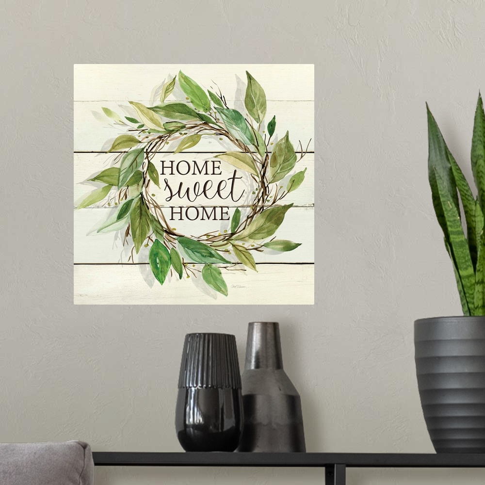 A modern room featuring A wreath of various watercolor leaves surround the words, "Home, sweet home" on shiplap.