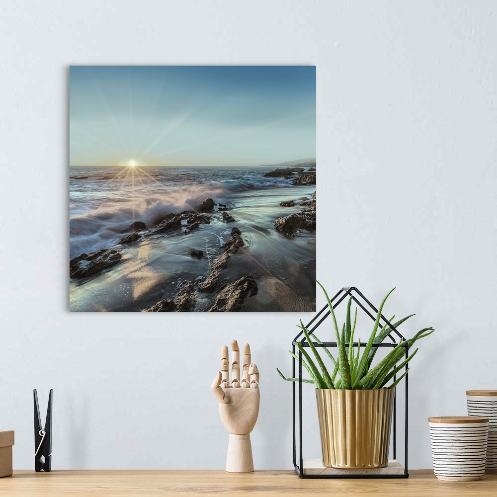 A bohemian room featuring Square photograph of ocean waves crashing on a rocky shore with the sun setting on the horizon li...