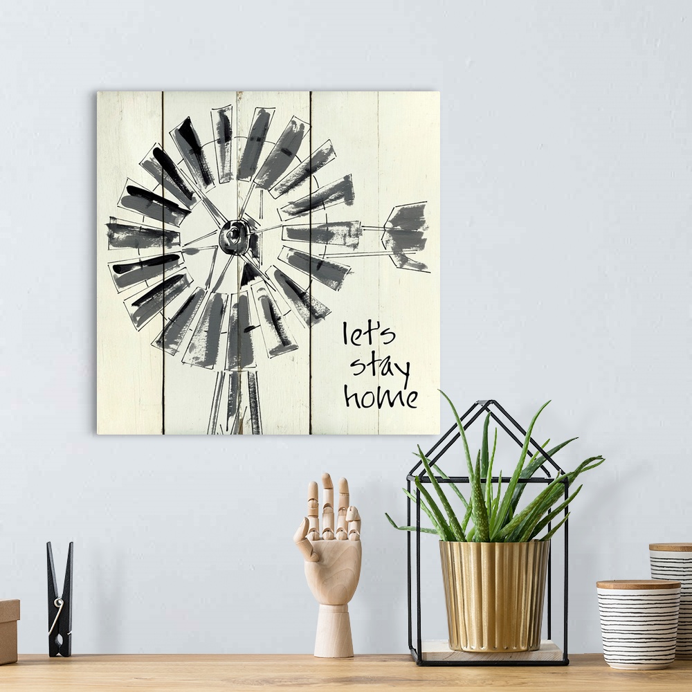 A bohemian room featuring 'Let's Stay Home' written on a square shiplap background with an illustration of a windmill.
