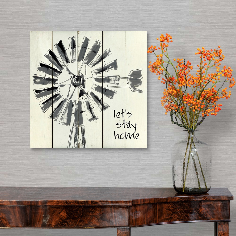 A traditional room featuring 'Let's Stay Home' written on a square shiplap background with an illustration of a windmill.