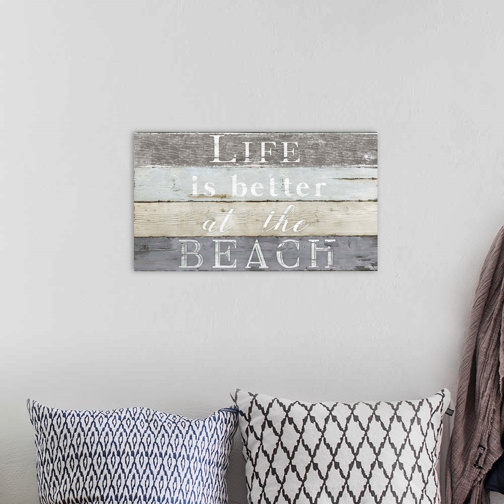 A bohemian room featuring Decorative artwork with the text "Life is Better at The Beach" against a wood plank backdrop.