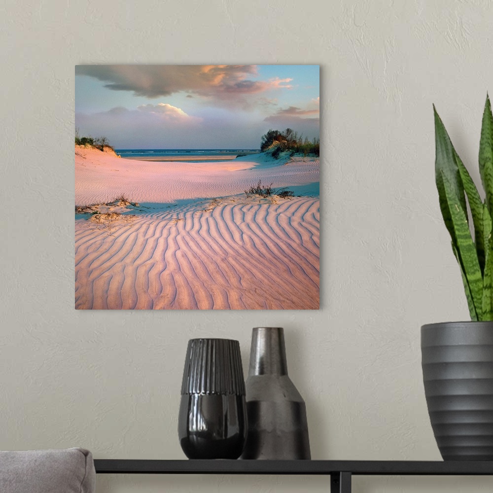 A modern room featuring Square landscape photograph  of a beach scene highlighting the texture in the pink toned sand.