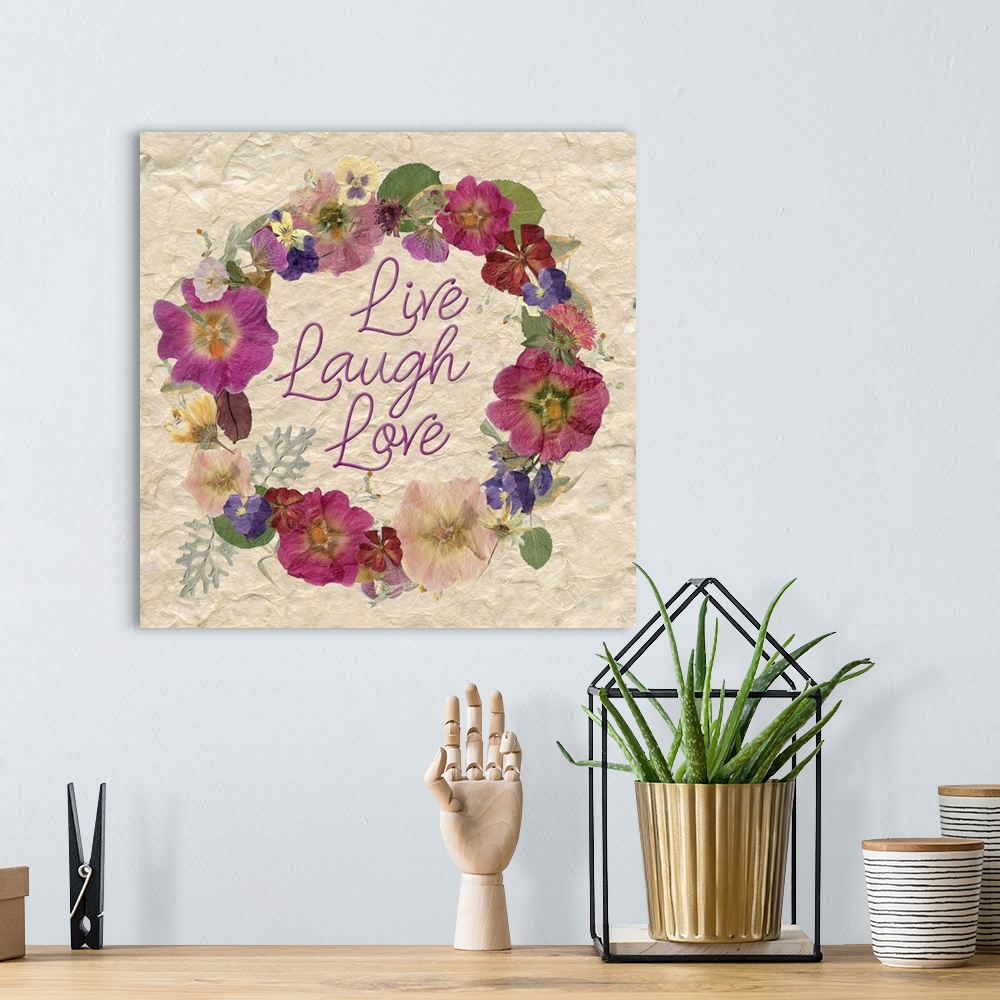 A bohemian room featuring A wreath of various dried flowers and foliage surround the words, "Live, laugh, love" on a natura...