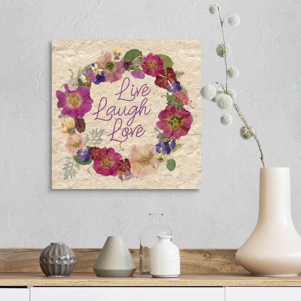 A farmhouse room featuring A wreath of various dried flowers and foliage surround the words, "Live, laugh, love" on a natura...