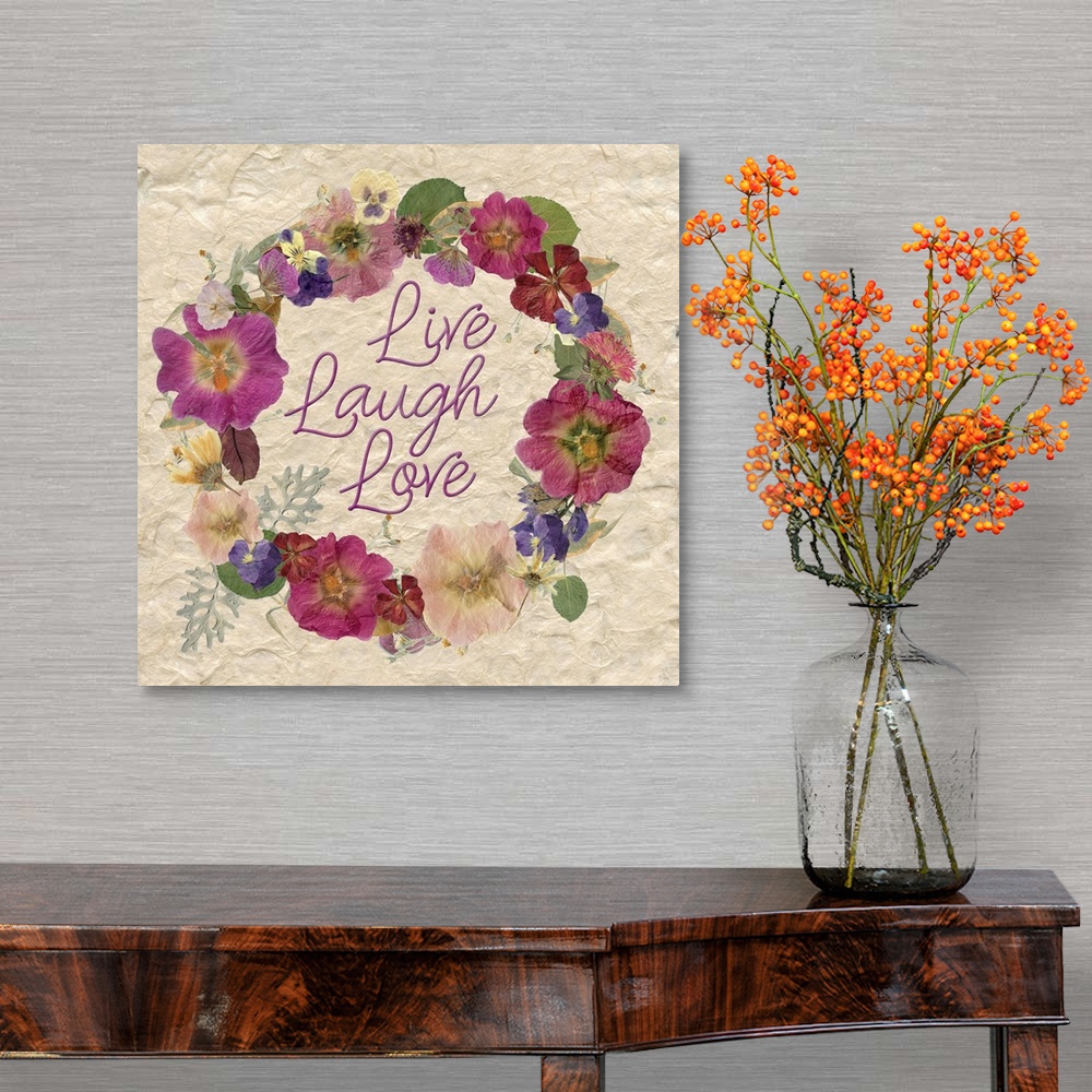 A traditional room featuring A wreath of various dried flowers and foliage surround the words, "Live, laugh, love" on a natura...