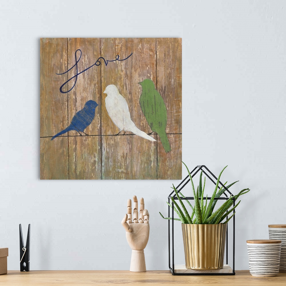 A bohemian room featuring A painting of three birds sitting on a line with the word ?Love? painted at the top on a wooden b...