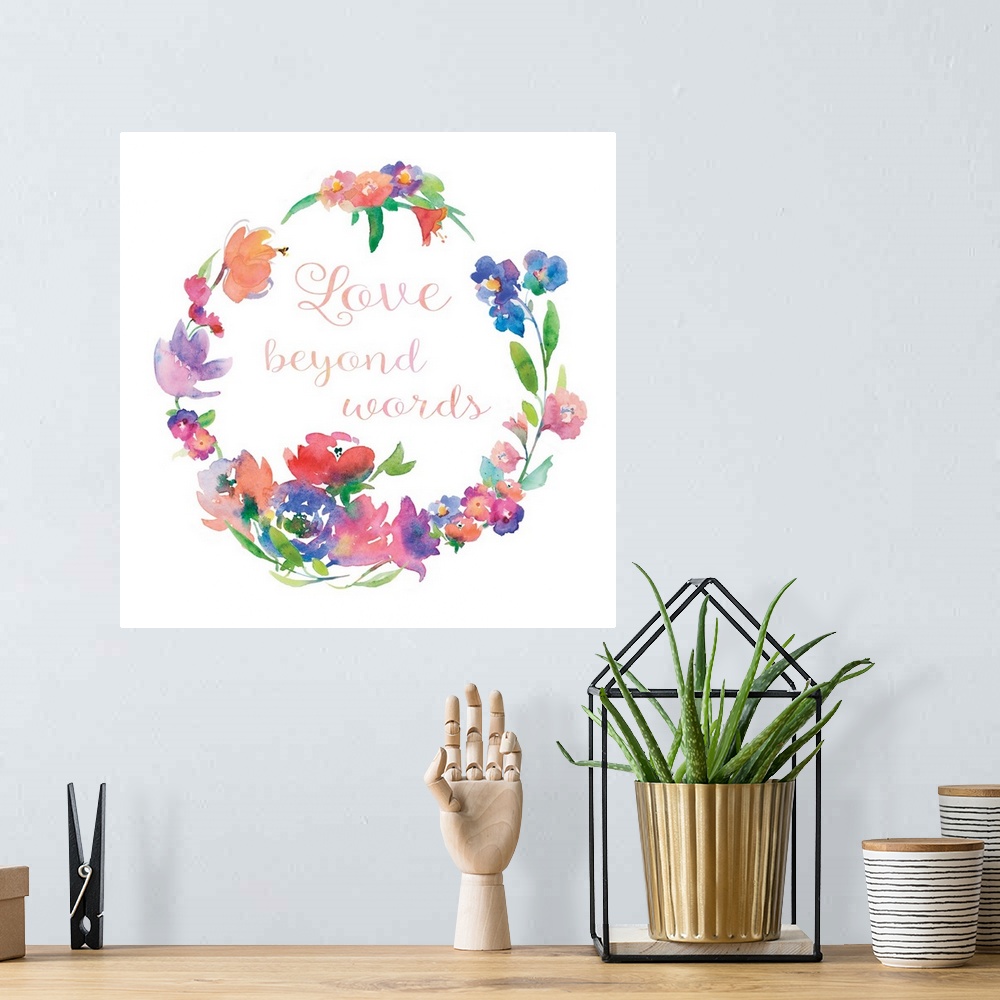 A bohemian room featuring "Love Beyond Words" written in cursive inside of a watercolor floral wreath on a white square bac...