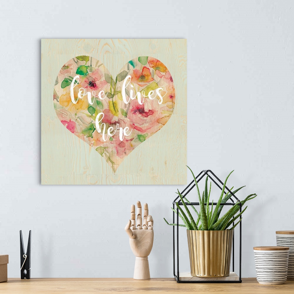A bohemian room featuring "Love Lives Here" written in white script inside a heart filled with watercolor flowers, all on a...
