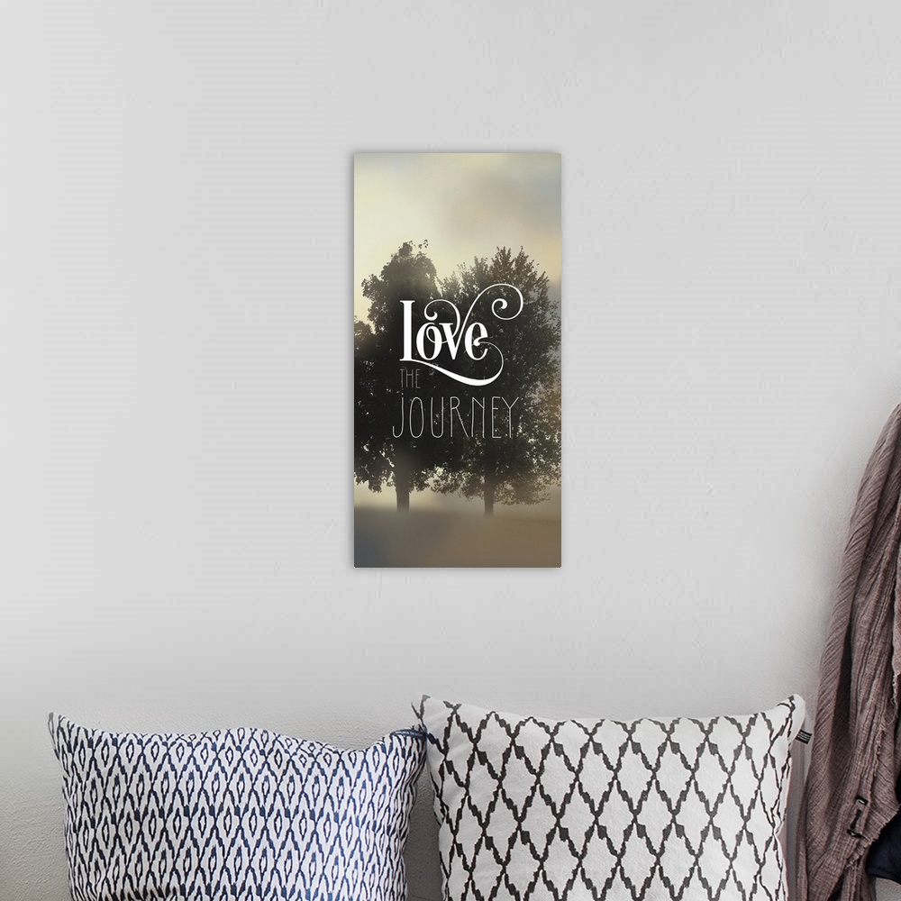 A bohemian room featuring "Love The Journey" written on top of a silhouette of two trees amongst fog.
