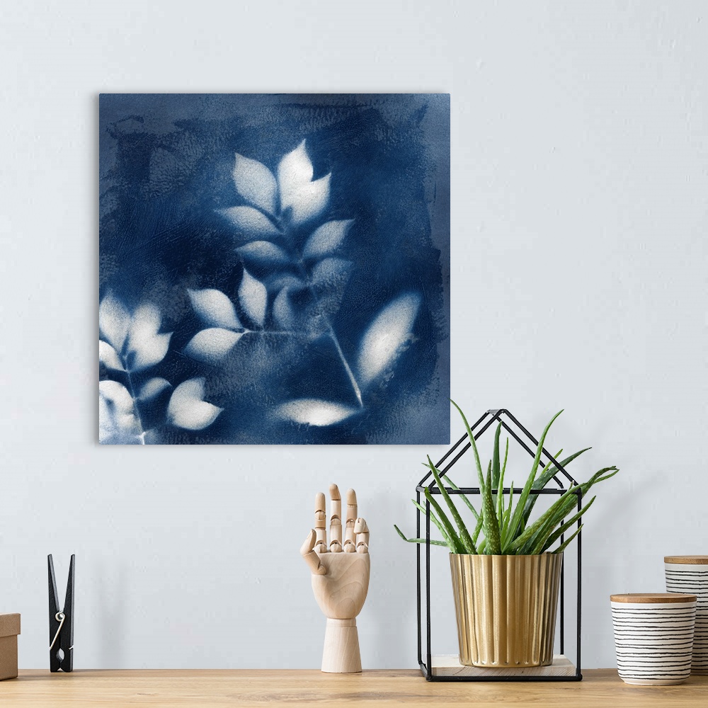 A bohemian room featuring Square indigo painting of white silhouettes of leaves.