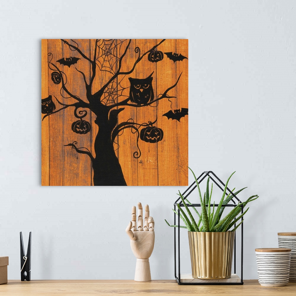 A bohemian room featuring A decorative Halloween painting of a spooky tree with owls, bats, jack o lanterns, and spider web...