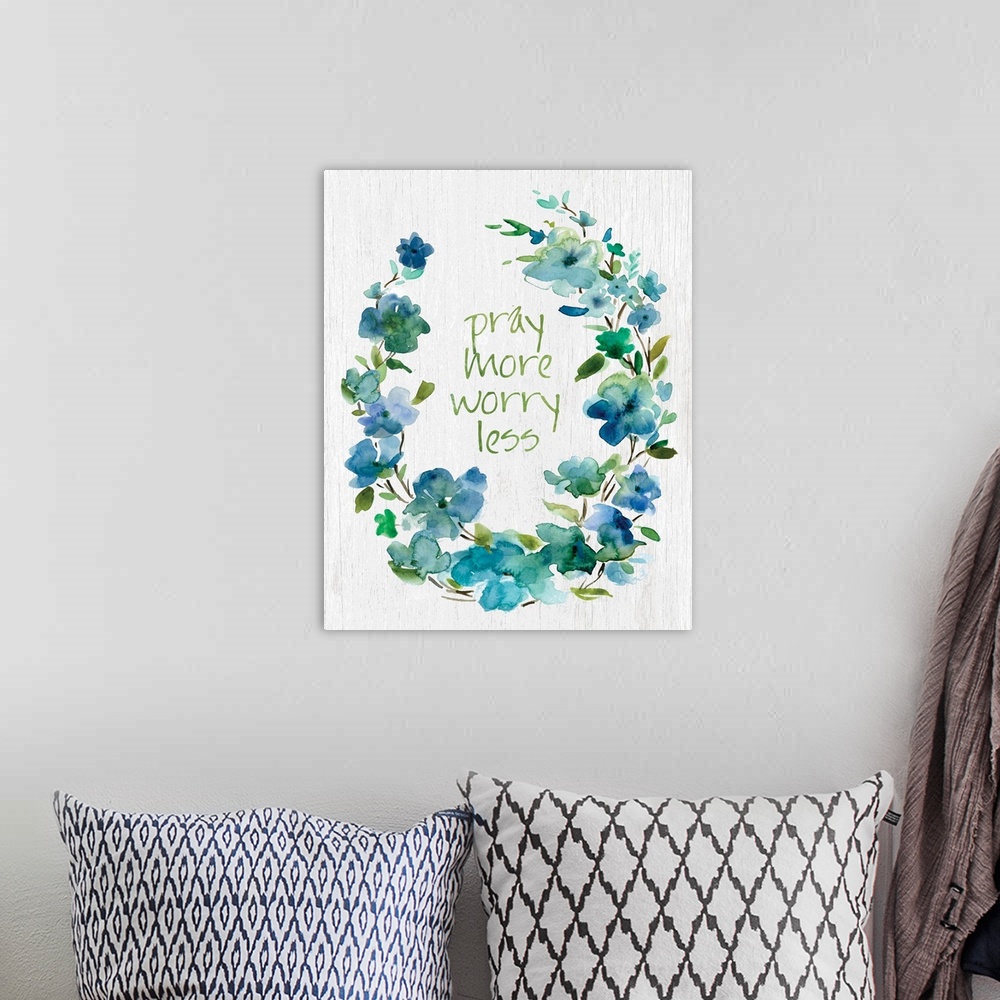 A bohemian room featuring "Pray More, Worry Less" placed on white textured background with blue flowers surrounding it.