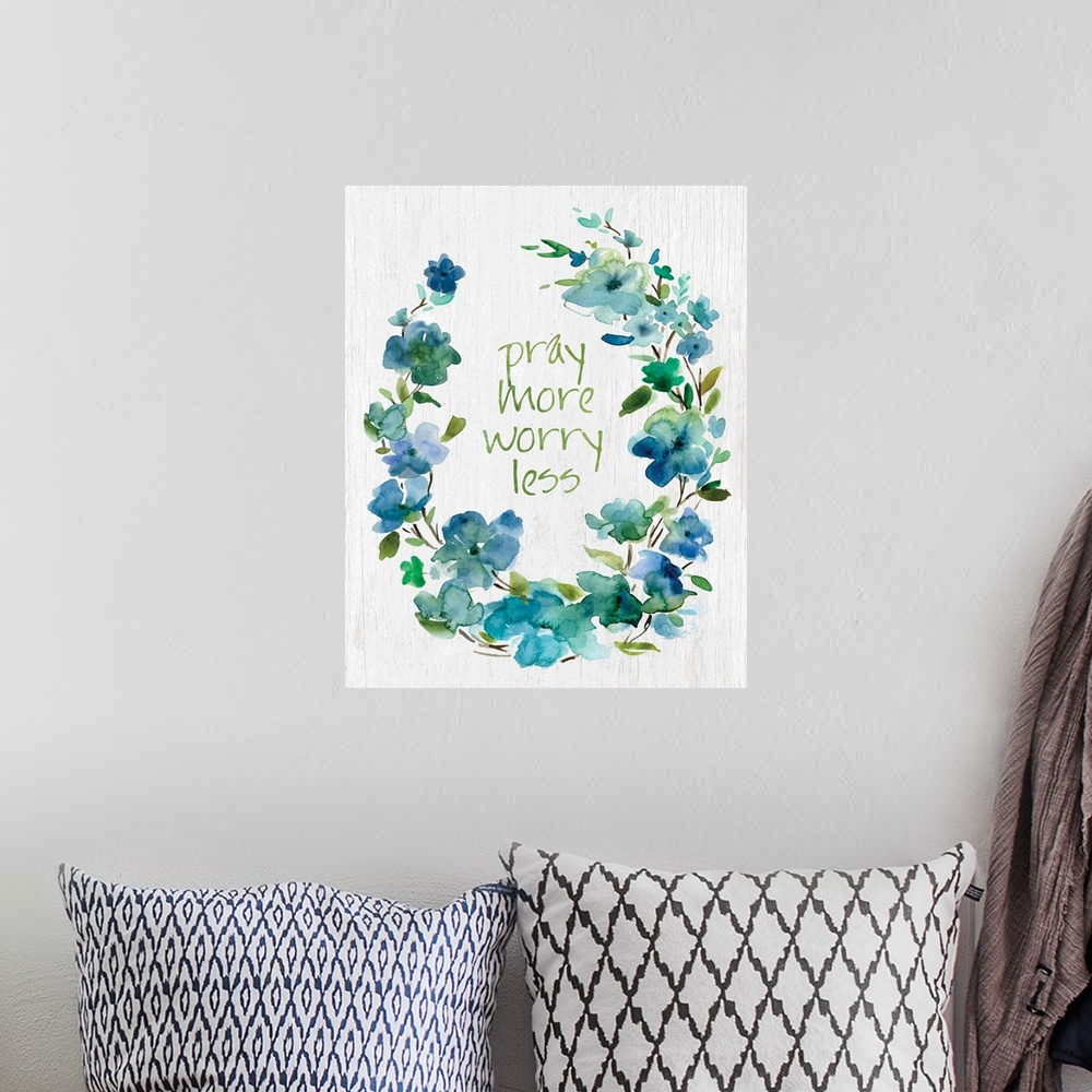 A bohemian room featuring "Pray More, Worry Less" placed on white textured background with blue flowers surrounding it.