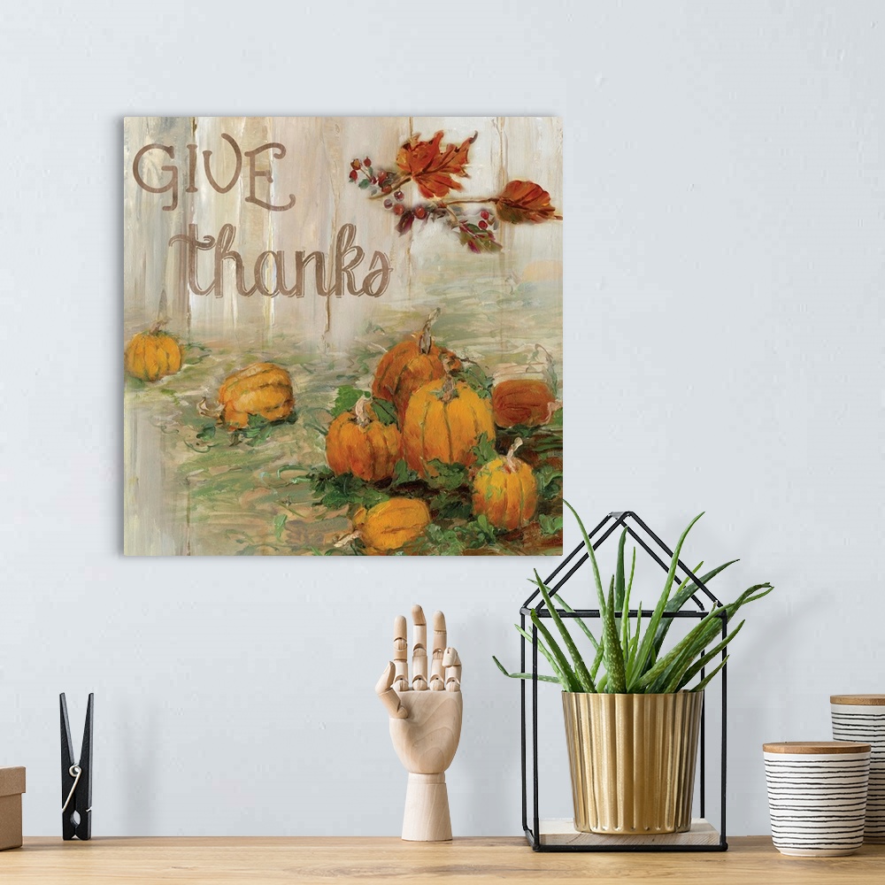 A bohemian room featuring "Give Thanks" written on a square canvas with illustrated pumpkins in a pumpkin patch and Fall le...