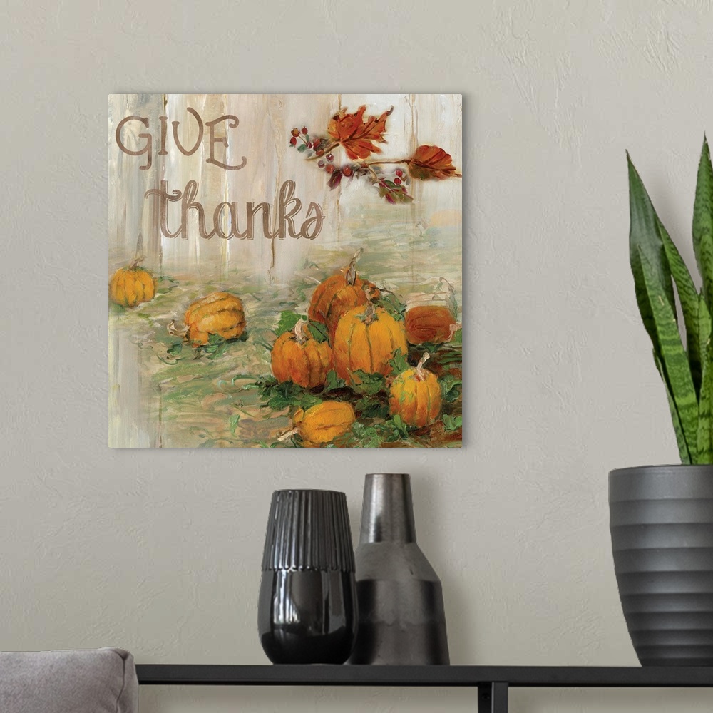 A modern room featuring "Give Thanks" written on a square canvas with illustrated pumpkins in a pumpkin patch and Fall le...