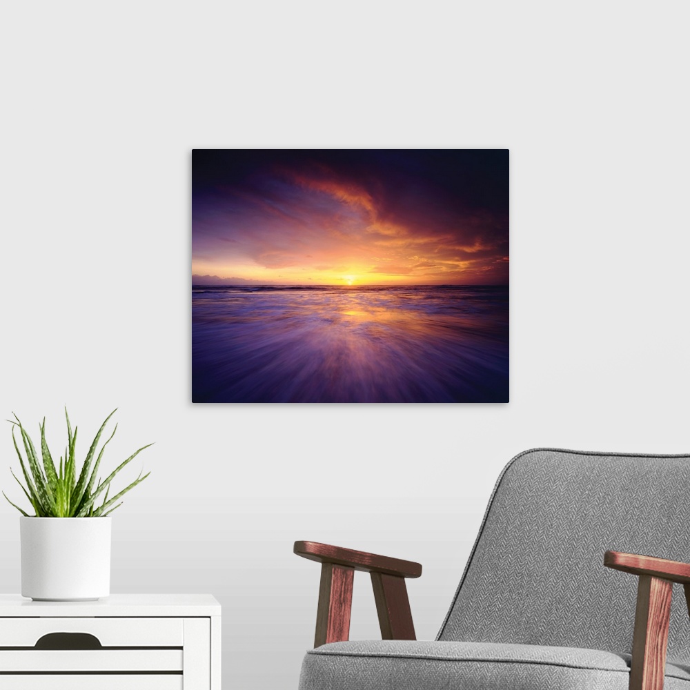 A modern room featuring Long exposure photograph of the sun setting on the ocean's horizon in shades of purple, pink, and...