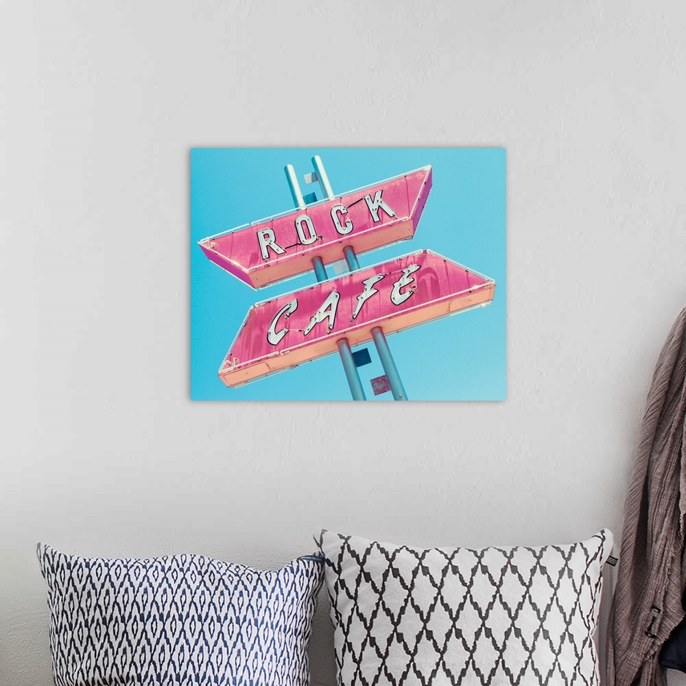A bohemian room featuring Photograph of a retro pink and white 'Rock Cafe' light up sign on a blue sky background.