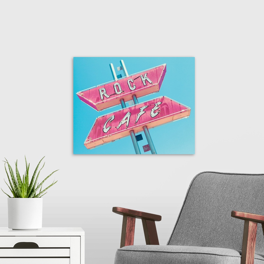 A modern room featuring Photograph of a retro pink and white 'Rock Cafe' light up sign on a blue sky background.
