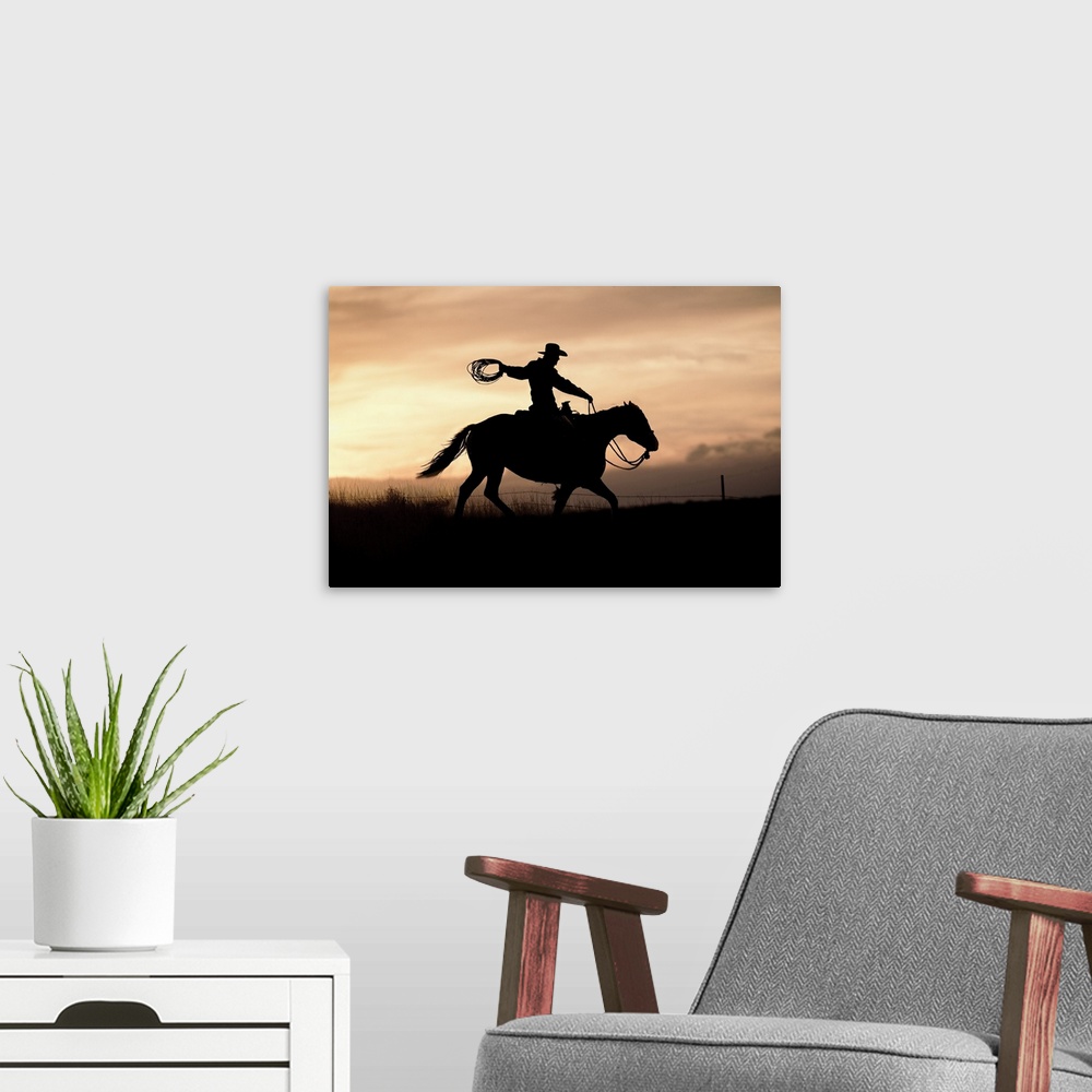 A modern room featuring A photograph of a silhouette of a cowboy riding a horse in a field with a sunset.