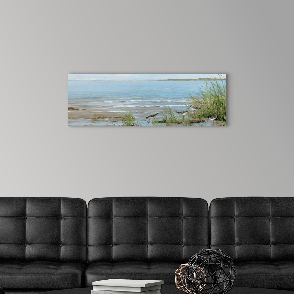 A modern room featuring A contemporary painting of a beach scene with birds foraging in the foreground and sailboats in t...