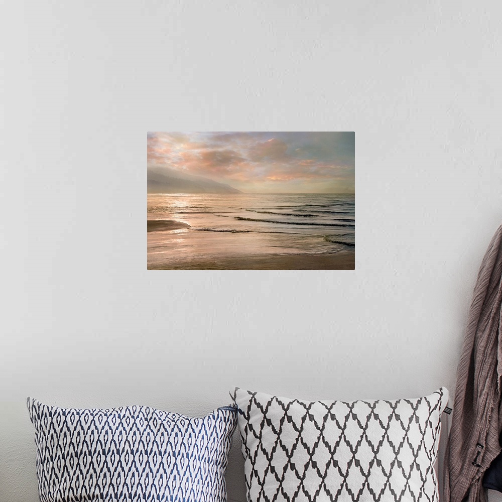A bohemian room featuring A photograph of small waves coming to shore with mountains in the background and a pink sunset.