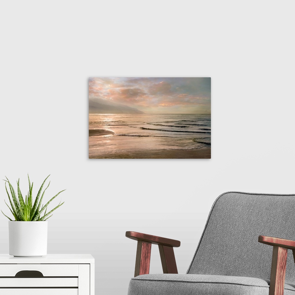 A modern room featuring A photograph of small waves coming to shore with mountains in the background and a pink sunset.