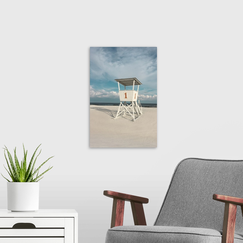 A modern room featuring A photo of a lifeguard tower on a cloudy day with an unoccupied beach in the background.