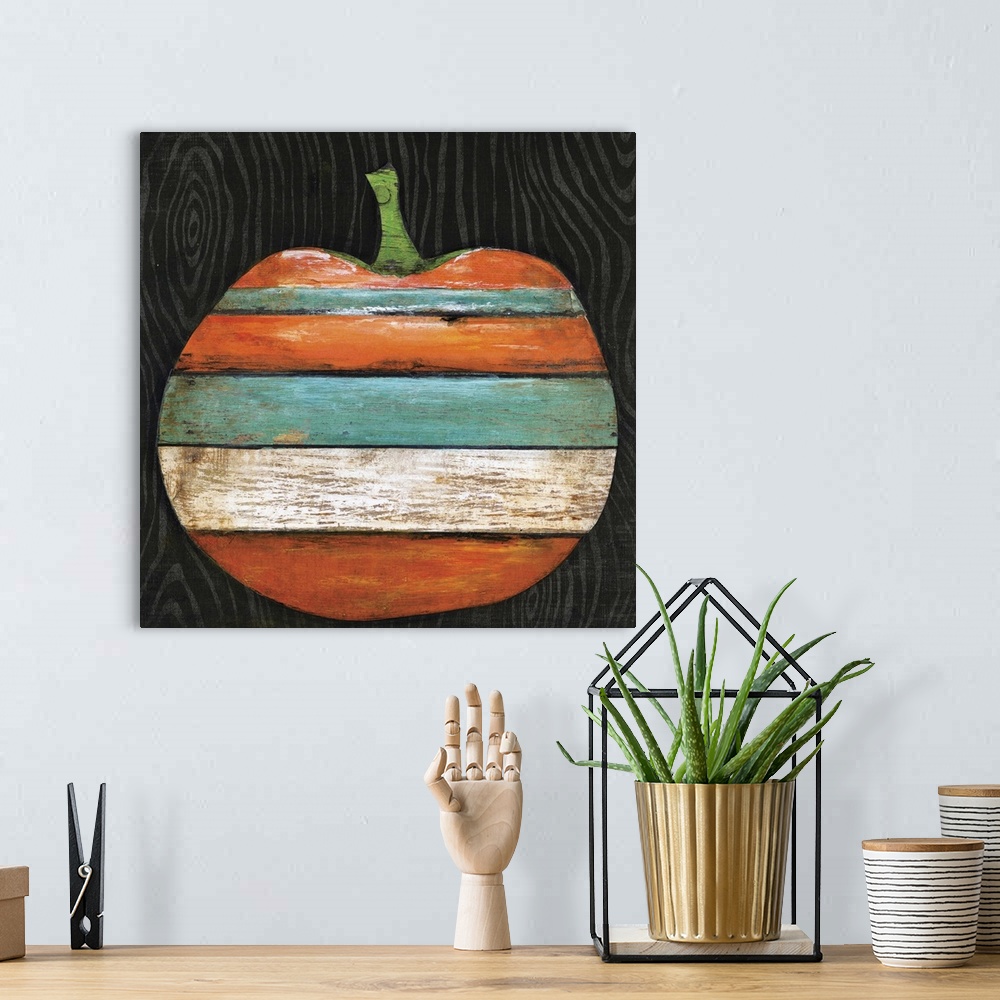 A bohemian room featuring A wood painting of an orange, teal, black, and white striped pumpkin on a black background.