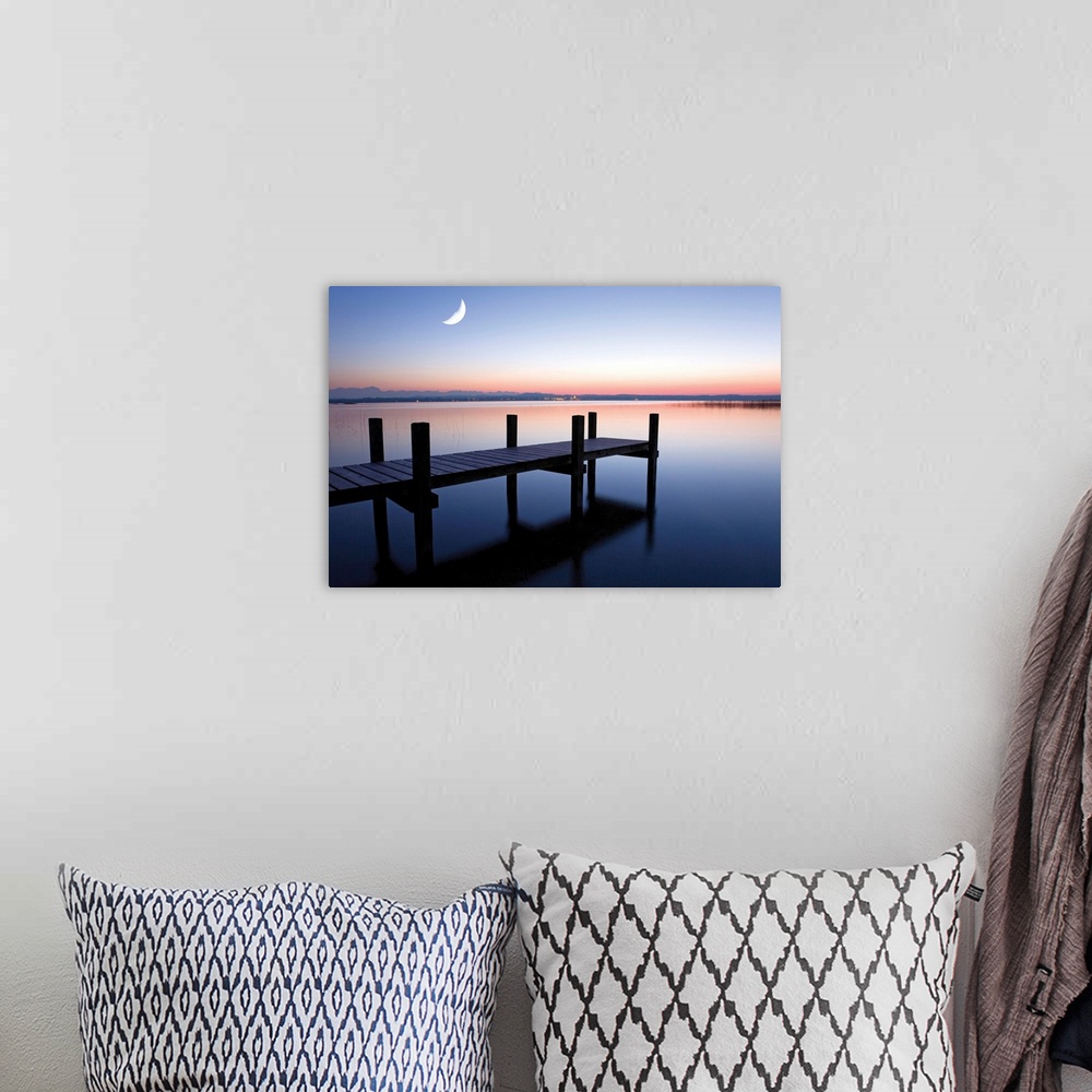 A bohemian room featuring Sunset photograph of a dock over calm water and a half moon in the sky.