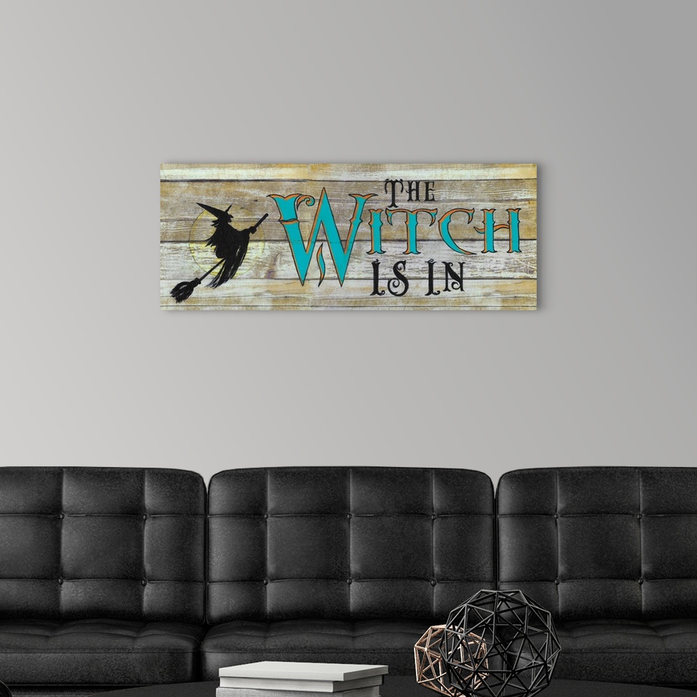 A modern room featuring A decorative Halloween painting of a witch riding a broomstick over the moon with the phrase ?The...