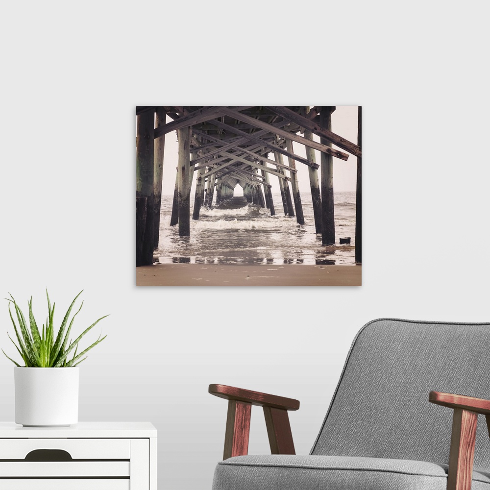 A modern room featuring Photograph, with a faded look, of under a pier at the beach.
