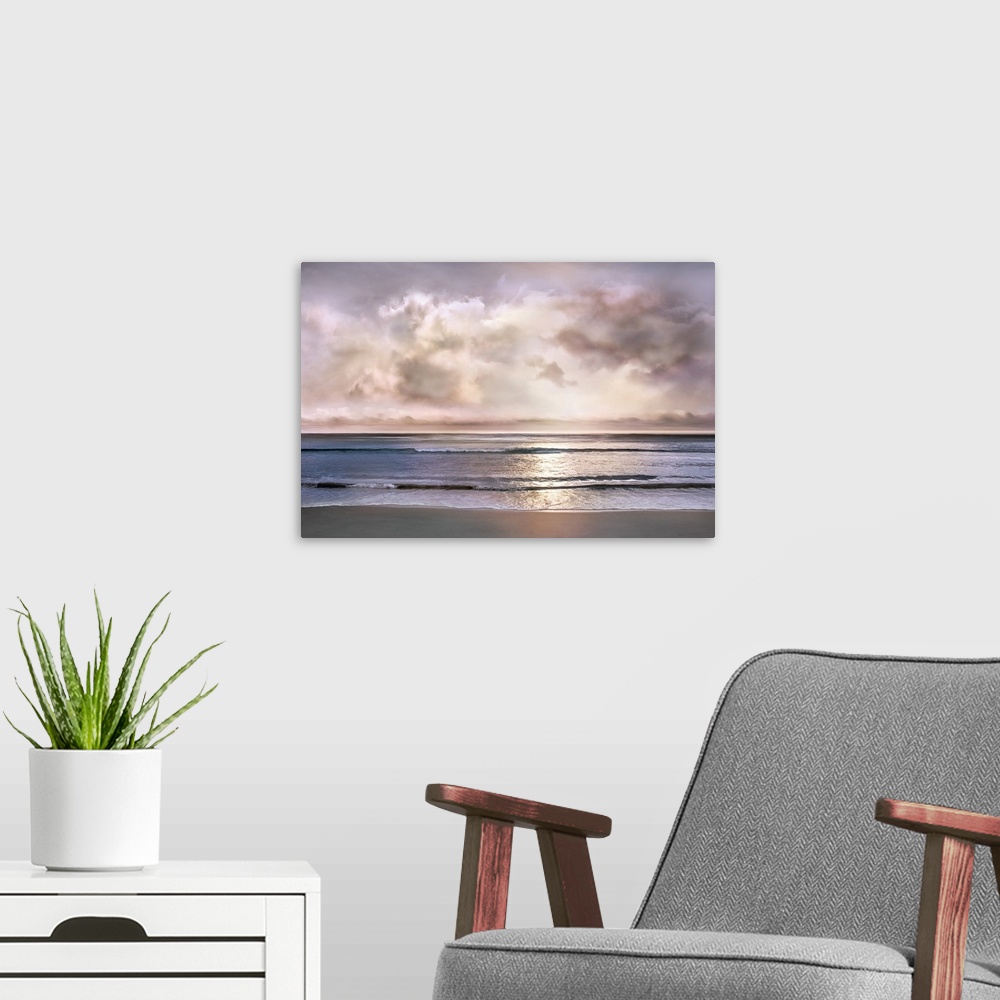 A modern room featuring Landscape photograph where the ocean and shore meet with a light pink and purple sunset pushing t...