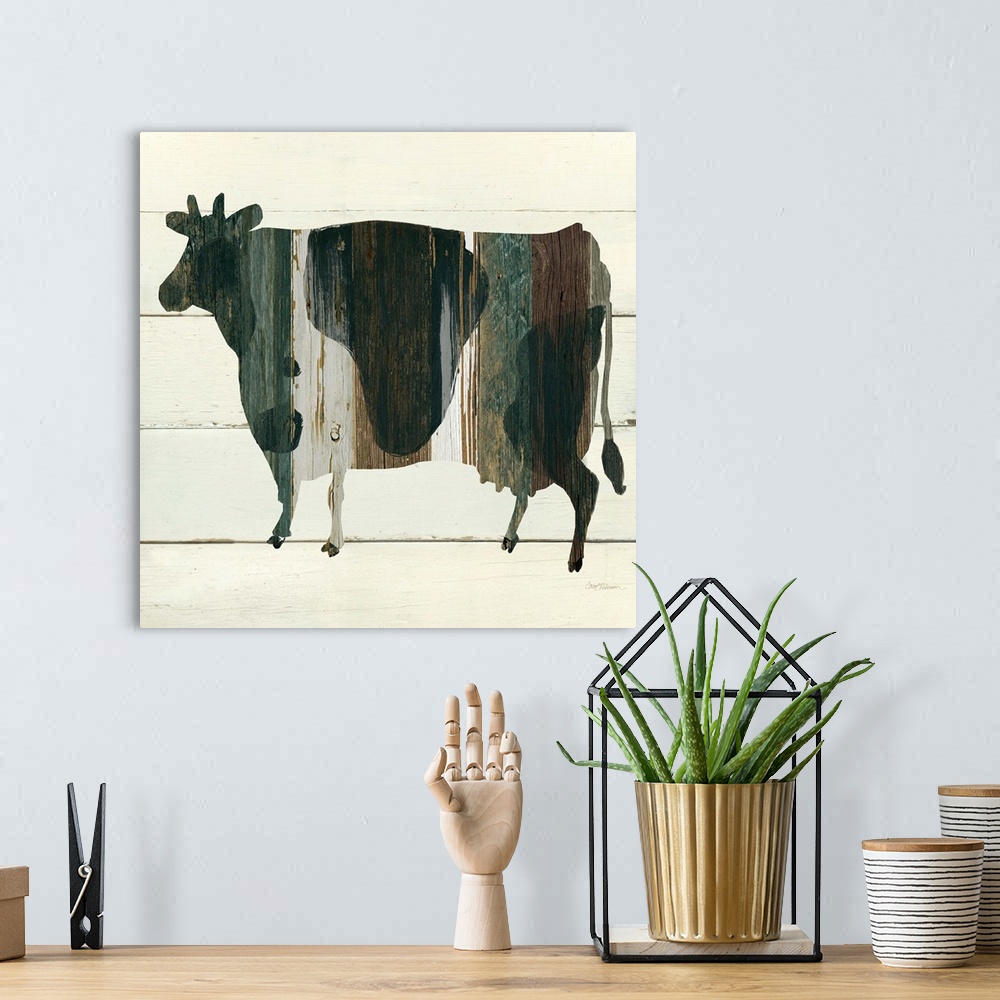 A bohemian room featuring A painting of a cow using multicolored stained wood placed on a white wooden background.