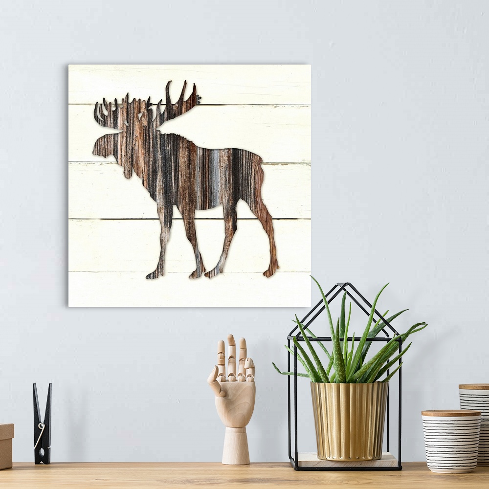 A bohemian room featuring Square decor of a dark brown wooden silhouette of a moose on a white wooden plant background.