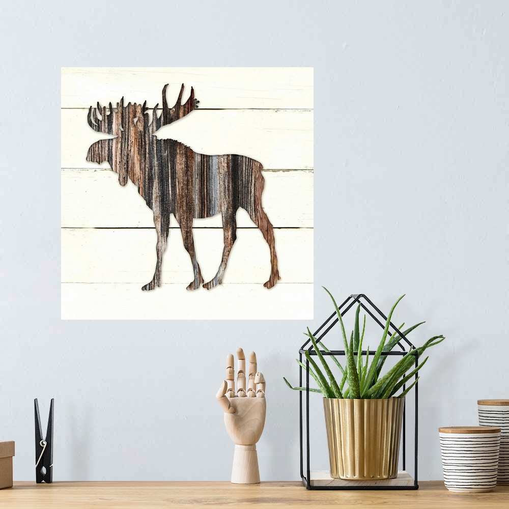 A bohemian room featuring Square decor of a dark brown wooden silhouette of a moose on a white wooden plant background.