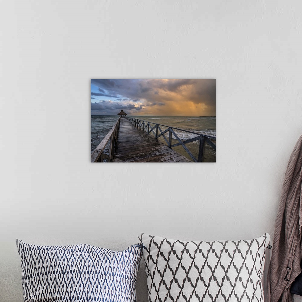 A bohemian room featuring Photograph of a dock over the ocean with an orange cloudy sunset.